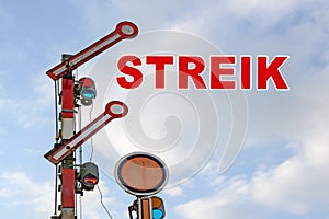 Railroad signal and German text Streik, meaning strike, against a blue sky with clouds, copy space