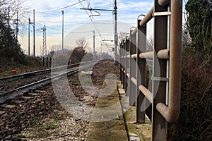 Railroad track borderd by bare trees that stretches to the horizon in the italian countryside in winter