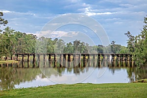 A railroad track bridge over a public lake called Cherokee Lake, in Thomasville Georgia on a Sunny day with a tranquil