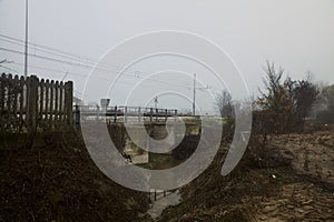 Railroad track next to a stream of water on a foggy day in autumn