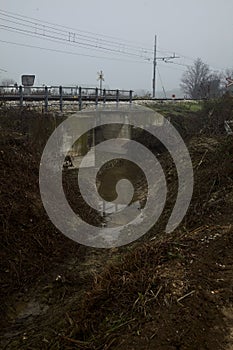 Railroad track next to a stream of water on a foggy day in autumn