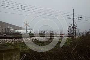 Railroad track next to a stream of water on a foggy day in autumn