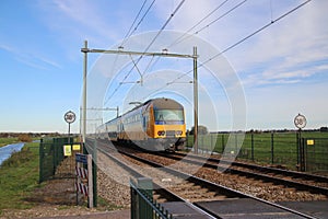 Railroad track with yellow blue dutch double decker train between Gouda and Rotterdam at Moordrecht.