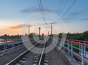 Railroad tracks on the bridge by the countryside in the evening