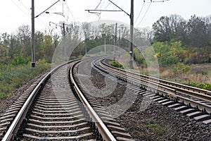 Railroad tracks in countryside with gray sky