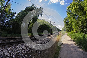 Railroad tracks and dirt road through UWA fisheye lens on a sunny day. Summer