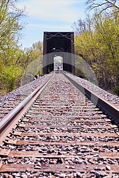 Railroad tracks leading to large metal bridge