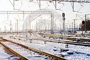 Railroad tracks in the snow. Commodity railway wagons, winter. High-voltage wires above the railway tracks. Beautiful sunset light