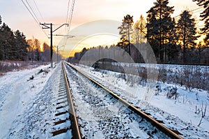 Railroad tracks in the winter forest at sunset