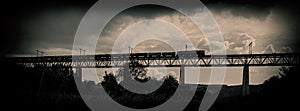 Railroad train moves along the bridge against a background of th