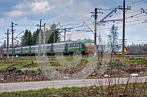 Railroad Train passing by a wooden rural house in a web of wires