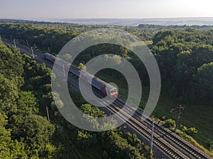 Railroad and Train in summer forest in foggy sunrise. Top view rural railway. Aerial view