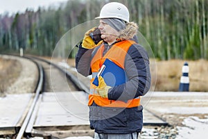 Railroad worker with documentation and smartp hone on railway crossing photo