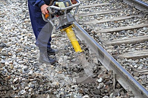 Railroad worker using vertical vibration tamper
