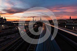 Railroads and bridges surrounded by buildings and lights with long exposure during the sunset