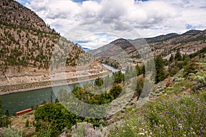 Railrod Tracks Running on Both Sides of a River in the Mountains and Cloudy Sky