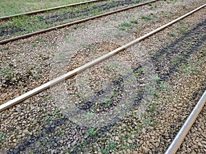 The rails go into the distance. Crushed stone, grass between the rails. Top view
