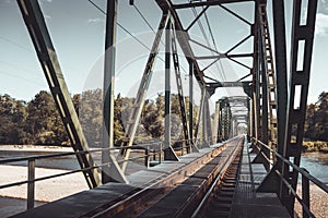 Railway bridge crossing river with forest in the backgorund