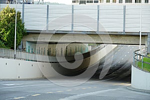 Railway bridge with traction lines and a noise protection wall closeup. Under it there is a multilane road with sidewalks.