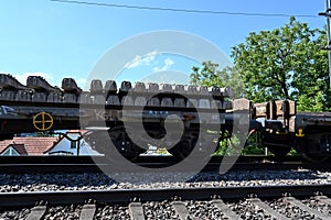 A railway carriage loaded with concrete sleepers stands on the rails.