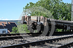 A railway carriage with train bumpers loaded with concrete sleepers stands on the rails.