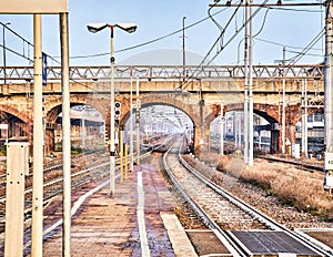 Railway with catenaries crossing a bricks bridge in an European train station