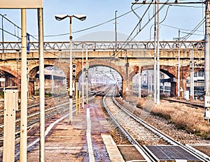 Railway with catenaries crossing a bricks bridge in an European train station photo