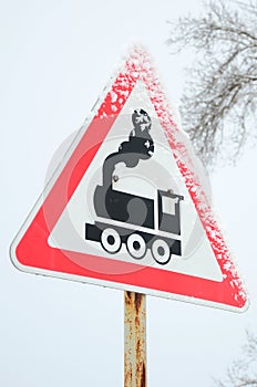 Railway crossing without barrier. A road sign depicting an old black locomotive, located in a red triangle