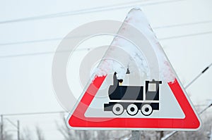 Railway crossing without barrier. A road sign depicting an old black locomotive, located in a red triangle