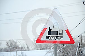 Railway crossing without barrier. A road sign depicting an old black locomotive, located in a red triangle