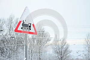 Railway crossing without barrier. A road sign depicting an old black locomotive, located in a red triangle