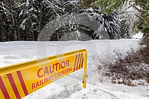 Railway crossing caution sign near train tracks in winter.