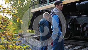 Railway crossing. The family stands near the railway and looks at the passing locomotive. Autumn Park, a picturesque