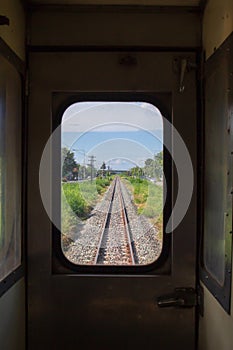 Railway crossing or junction road with railroad view from window or door mirror inside the train bogy.