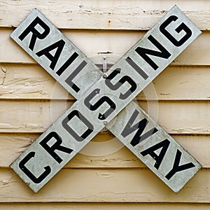 A railway crossing sign on the side of a weatherboard building photo