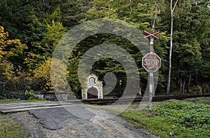 A railway crossing with a trail mark and a small yellow chapel