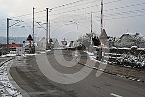 Railway crossing in village Urdorf, Switzerland in winter, captured with open barriers.