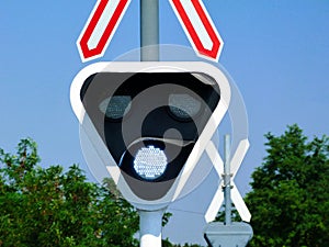 railway crossing. white circular light semaphore. train rail crossing signal in triangular sign plate under red lights