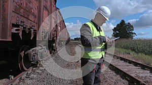 Railway employee using smart phone near wagons