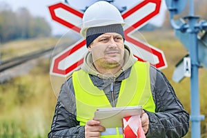 Railway engineer with tablet PC near warning signs