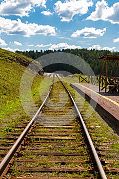Railway, going far beyond the horizon; It passes through the flat terrain, along sides of fields and meadows with yellow