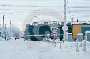 Railway grade cross with passing train, winter season. Car waiting for driving