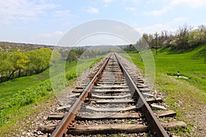 Railway on the green meadow. Rails and sleepers. Railway tracks in rural areas. Green meadows and young trees