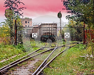 The railway line adjoins the closed lattice metal gate, behind which the rails diverge in two different directions and