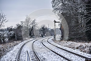 Railway line bending to the right in the snow with signal to the right of the line in the countryside