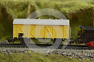 Railway model with yellow freight train car and landscape details