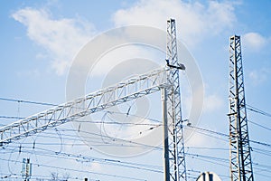 Railway overhead line system with lattice masts, catenary wires and structural support beams showing electrical infrastructure