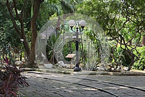 Railway rail at a park, stone road, street lamp and forest