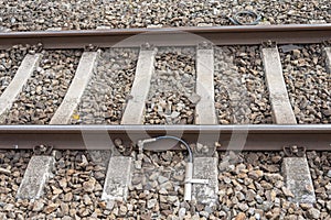 The railway rails are earthed with a metal cable to the concrete sleepers.