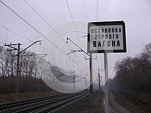 Railway rails in the fog with a sign stop the first car at the station